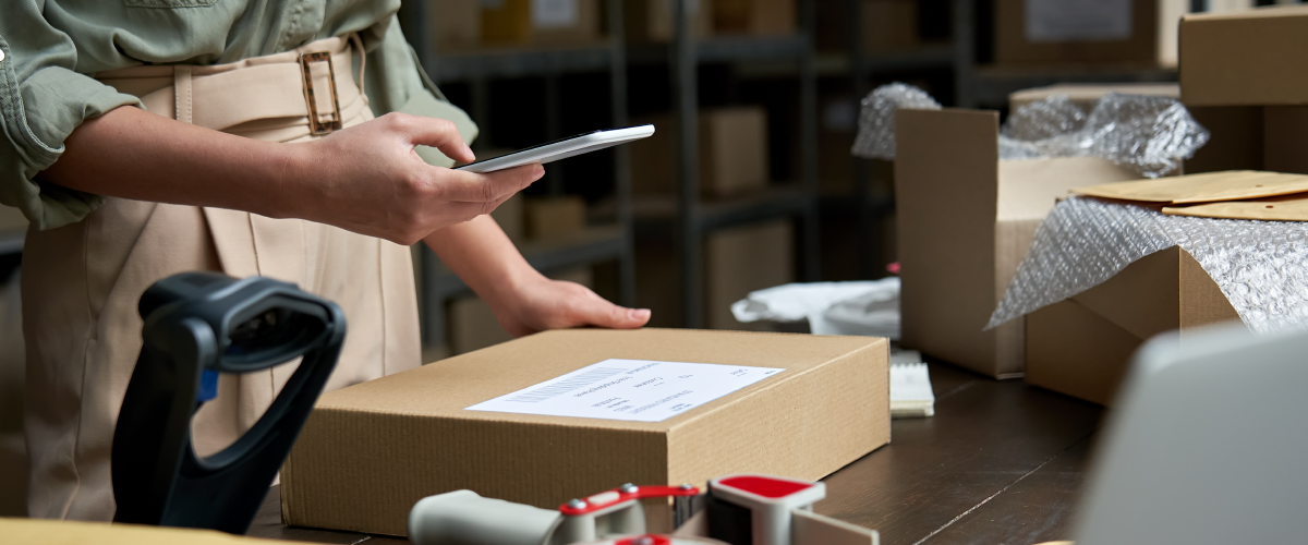 A person scans a code on a parcel using their phone on a workstation to show the importance of everyday tools working with logistics tech